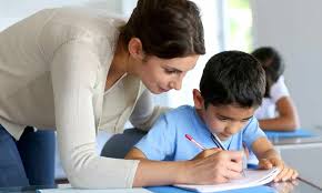 a woman helping a boy write on a book