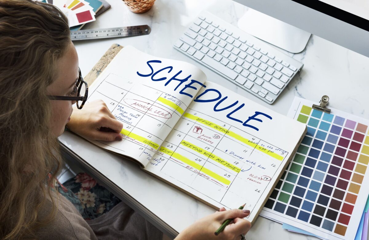 Student planning a study schedule with a notebook, calendar, and clock